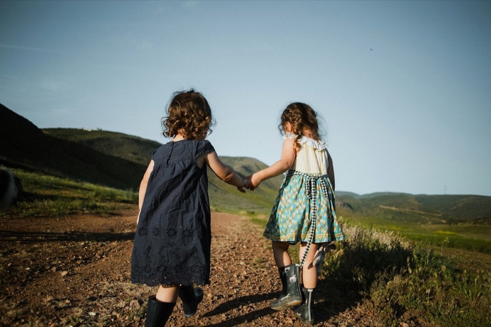 Two girls holding hands on a country path